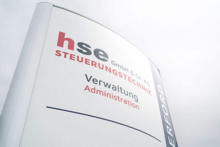 Pylon mit der Aufschrift hse Steuerungstechnik GmbH & Co KG vor grauem Himmel