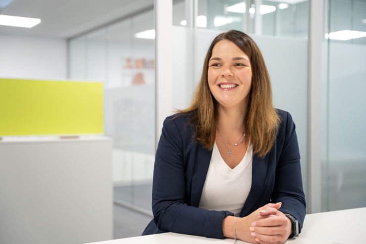 Eine lächelnde Mitarbeiterin der Stadtwerke Lübbecke mit gefalteten Händen am Tisch